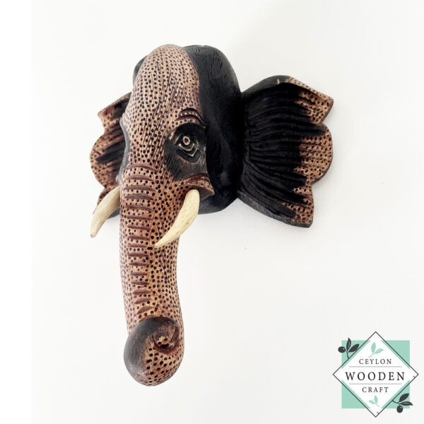 Hand-carved wooden elephant face sculpture with tusks. Made from mahogany wood. A symbol of luck and wisdom. Perfect for home decor or gifting.