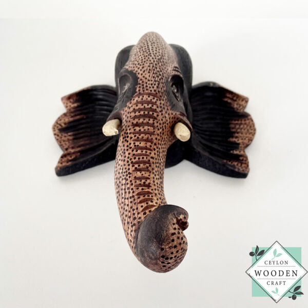 Hand-carved wooden elephant face sculpture with tusks. Made from mahogany wood. A symbol of luck and wisdom. Perfect for home decor or gifting.