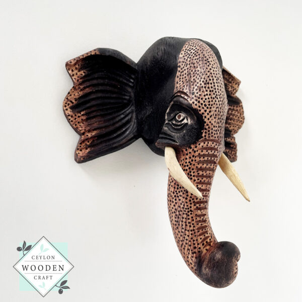 Hand-carved wooden elephant face sculpture with tusks. Made from mahogany wood. A symbol of luck and wisdom. Perfect for home decor or gifting.